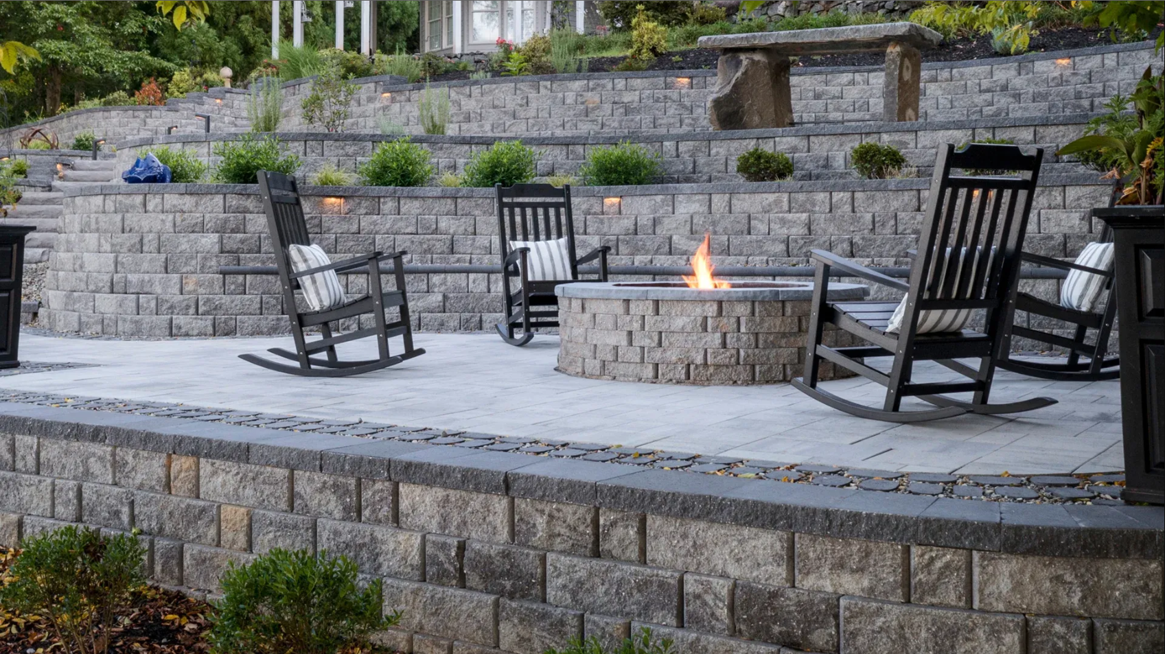 grey stone patio fire pit with rocking chairs around it