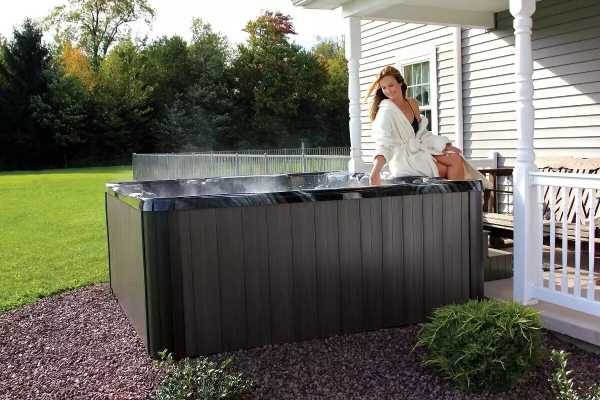 Hot Tub Buyer's Guide - Woman sitting on the edge of a hot tub touching the water